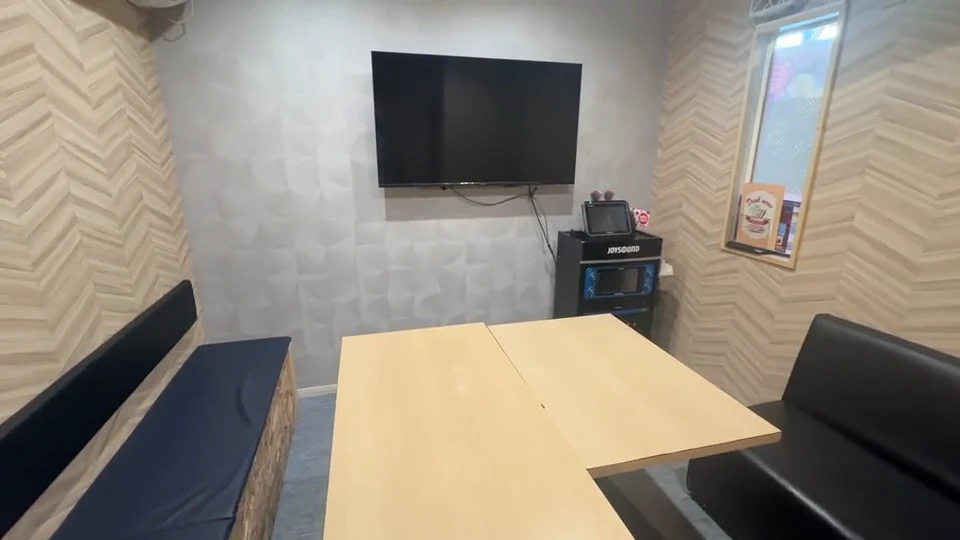 カラオケWAVE江の島店の客室。ベンチ席とテーブル、壁掛けのモニターがある